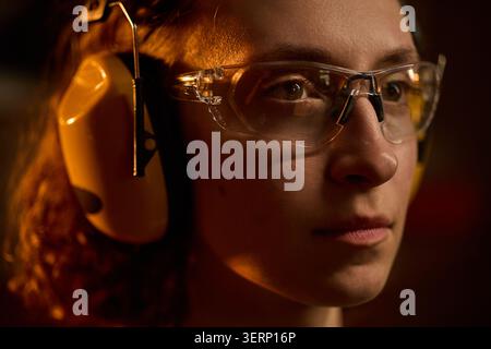 Donna adulta che indossa occhiali protettivi nel laboratorio di falegnameria Foto Stock