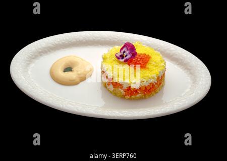 Elegante insalata a strati con caviale e decorazioni floreali Foto Stock