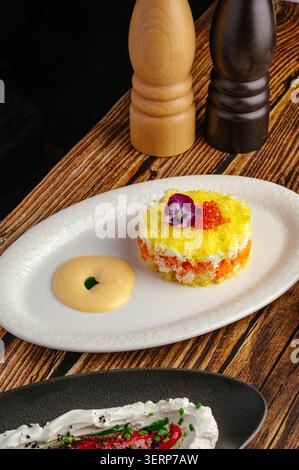 Insalata a strati con caviale rosso e contorno floreale Foto Stock