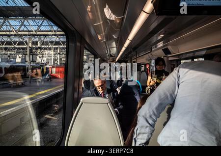 I pendolari si imbarcano su un affollato treno della South Western Railway alla stazione di Waterloo durante una calda serata, nel centro di Londra, Inghilterra, Regno Unito Foto Stock