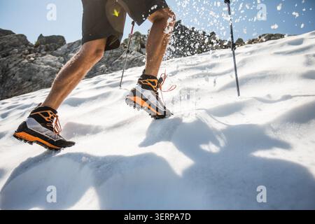 Primo piano di un uomo che corre in salita sulla neve Foto Stock