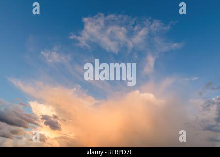 Bellissime nuvole e sfondo blu del cielo al tramonto con toni arancioni creati dal sole a Norfolk Inghilterra Regno Unito. Sfondo Cloudscape e Skyscape Foto Stock
