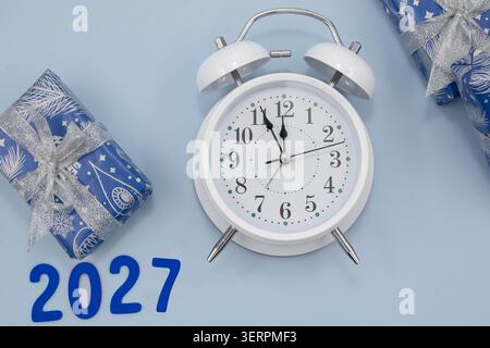Sveglia bianca con 2027 numeri e regali avvolti su sfondo blu Foto Stock