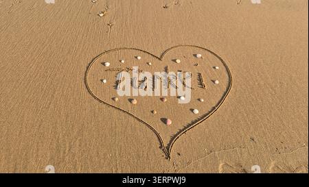 Heart Shape disegnato in sabbia con la parola tacchino sulla spiaggia di Ocean Waves Foto Stock