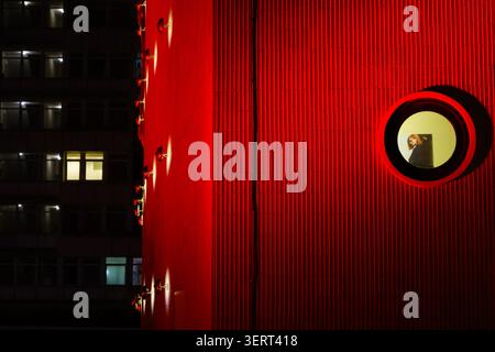 Facciata rossa illuminata con finestra rotonda e figura, cinema Zoo Palast, Berlino, atmosfera notturna Foto Stock