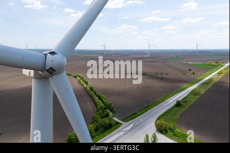 Primo piano di una turbina eolica con un parco eolico all'orizzonte Foto Stock