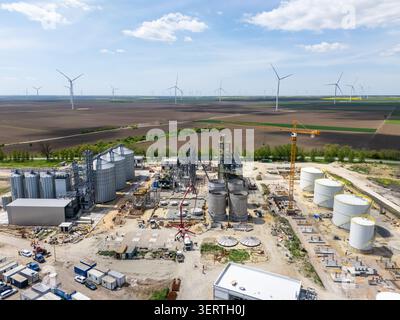 Costruzione di un moderno terminale agricolo per cereali con turbine eoliche all'orizzonte. Foto Stock