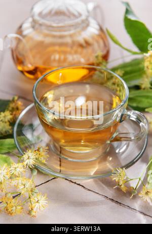 Tisane tisane in una teiera di vetro e tazza, con fiori di tiglio freschi Foto Stock