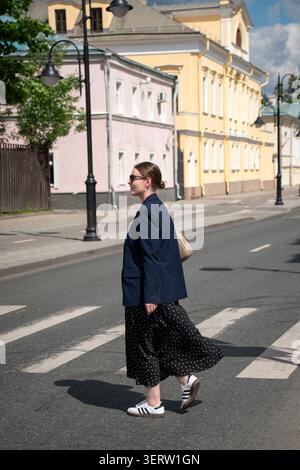 Mosca, Russia - 24 maggio 2026: Donna attraversa l'attraversamento pedonale in via Pyatnitskaya con edifici storici e paesaggi tradizionali. Urbano Foto Stock