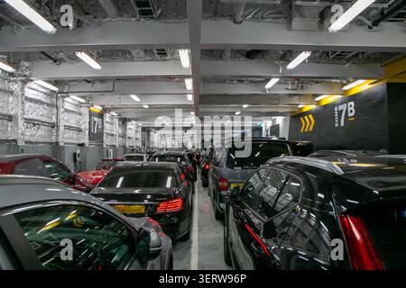 Affollato ponte interno di un traghetto per auto commerciali che attraversa la Manica. L'auto rossa e le altre auto sono parcheggiate bene Foto Stock