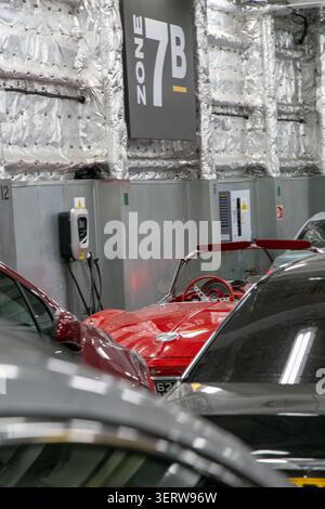 Affollato ponte interno di un traghetto per auto commerciali che attraversa la Manica. L'auto rossa e le altre auto sono parcheggiate bene Foto Stock