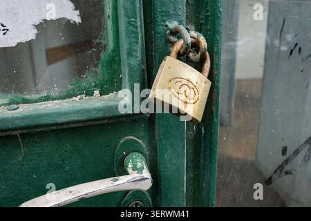 Un primo piano di una porta verde intemprata con un lucchetto in ottone appeso su di essa. Foto Stock