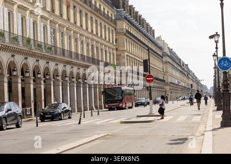 Una strada trafficata della città mostra autobus e auto mentre le persone camminano lungo il marciapiede. Gli alti edifici fiancheggiano entrambi i lati della strada sotto un cielo limpido Foto Stock