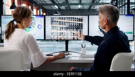 Due ingegneri discutono la progettazione di edifici 3D utilizzando il software BIM sullo schermo del computer. Foto Stock