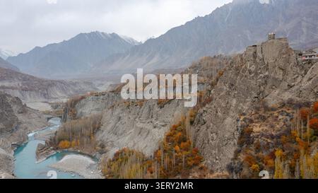 Vista aerea del forte di Altit arroccato su una scogliera rocciosa che si affaccia sul fiume Hunza con fogliame autunnale e montagne sullo sfondo, Altit, Gilgit, Pak Foto Stock