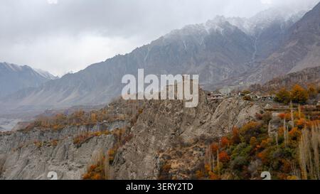 Vista aerea del forte di Altit arroccato su una scogliera rocciosa circondata da alberi autunnali e montagne innevate ad Altit, Gilgit, Pakistan. Foto Stock