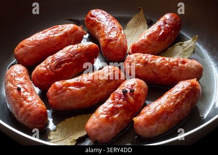 Salsicce di carne fritte da vicino. Salsicce speziate in una padella. Foto Stock