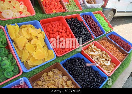 Vista laterale delle fette assortite di albicocche secche, mirtilli e mele esposte in vassoi colorati in un mercato locale nel Kashmir, India. Foto Stock
