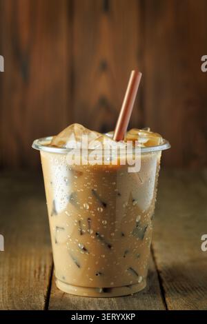 Caffè freddo freddo in una tazza di plastica trasparente posizionata su un tavolo in legno invecchiato Foto Stock