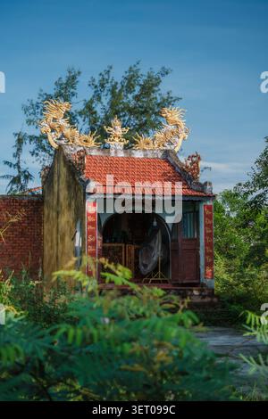 Tradizionale edificio di santuario asiatico con statue di draghi dorati sul tetto Foto Stock