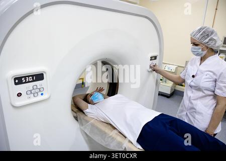 Tecnico di radiologia che esegue un esame di scansione TC su un paziente adulto in un ospedale moderno Foto Stock