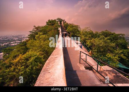 Splendide viste panoramiche sulla città di Udaipur e sul lago Pichola, circondate da architettura storica, verdi colline e suggestivo cielo serale. Foto Stock