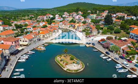 Villaggio di pescatori e porto di Vrboska dall'alto, con case tradizionali, barche e una piccola isola nel canale Foto Stock