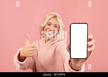 Giovane donna sorridente con telefono che mostra schermo vuoto, impostazione Casa, Copia spazio Foto Stock