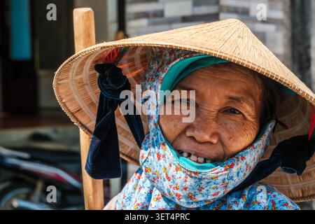 Ritratto ravvicinato di un'anziana donna asiatica sorridente che indossa un tradizionale cappello conico Foto Stock