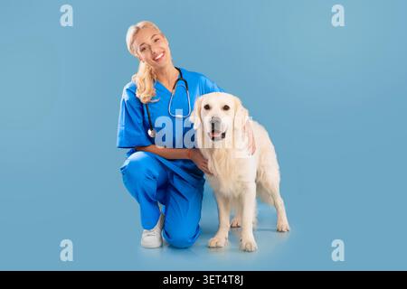 Felice donna veterinaria sorridente con Golden Retriever Dog in clinica, concetto di assistenza sanitaria Foto Stock