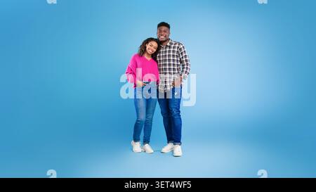 Giovane coppia nera sorridente in posa insieme a Joyful Expression, ambientazione Studio Foto Stock