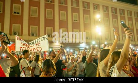 Tirana, Albania – 20 giugno 2026: I manifestanti tengono i telefoni cellulari e gli striscioni politici durante una protesta notturna affollata. Foto Stock