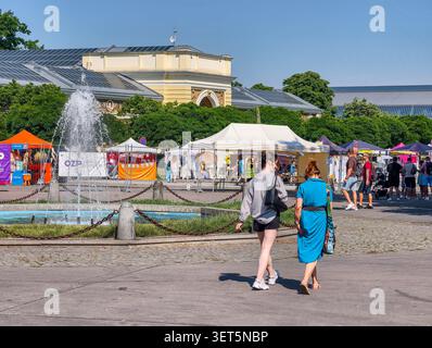Praga, Repubblica Ceca - 21 giugno 2026: I visitatori possono godersi una giornata di sole alla mostra di Praga, passeggiando attraverso un'affollata area di mercato all'aperto vicino a una fontana Foto Stock