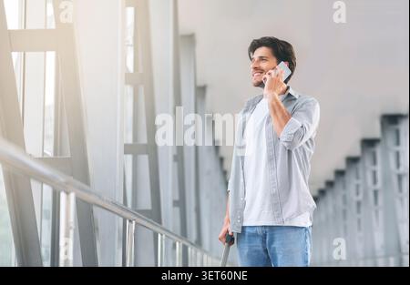 Giovane uomo parlando al telefono nel terminal dell'aeroporto Foto Stock