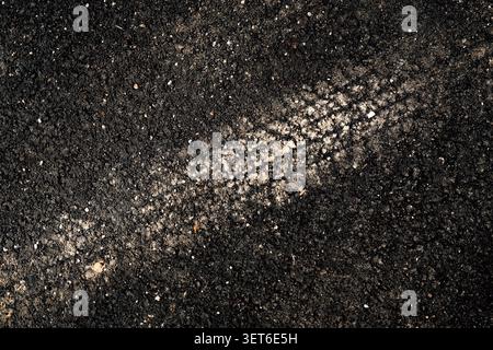 Impronta di un singolo cingolo su sabbia scura primo piano struttura e schema, vista dall'alto Foto Stock
