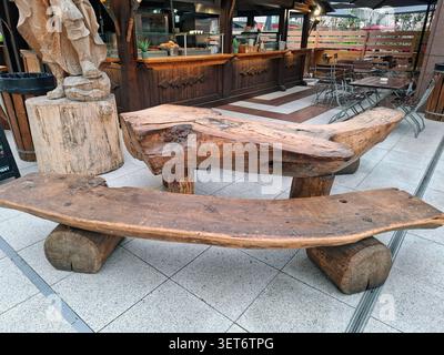FRANCOFORTE SUL MENO, Germania - 1° novembre 2025. Un tavolo rustico in legno e panche fatte di legno spesso sono collocati in un'area salotto all'aperto di un Cafe i Foto Stock