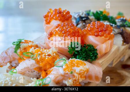 Set di involtini di salmone conditi con caviale e sushi di salmone bruciato su un vassoio di legno nel ristorante giapponese. Cibo giapponese. Foto Stock