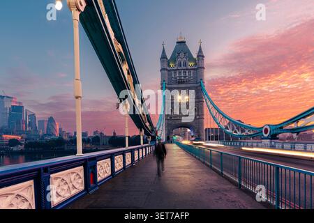 Sagoma del passeggero medio adulto che cammina sul Tower Bridge di Londra durante la drammatica alba mattutina. Destinazione di viaggio europea, storico Foto Stock