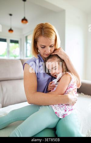 La madre abbraccia la figlia in un momento tenero a casa Foto Stock