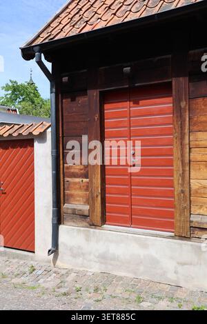 Vecchia porta rossa in legno a Visby, Gotland, Svezia, situata in uno storico edificio medievale in pietra. Foto Stock