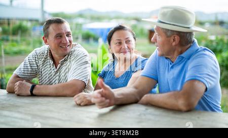 Agricoltori felici che parlano a tavola villaggio Foto Stock