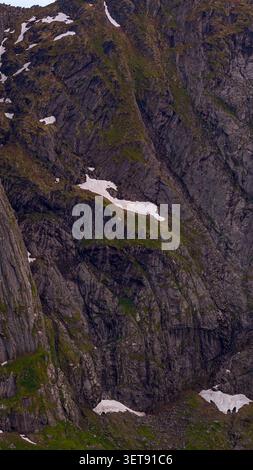 Suggestivo panorama delle montagne Lofoten caratterizzato da ripide scogliere colonnari di basalto con muschio e licheni, macchie di neve sparse, che mettono in risalto il forte Foto Stock