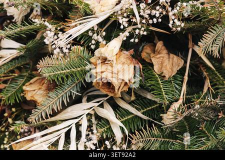 Corona rustica commemorativa con fiori secchi e rami sempreverdi. Sfondo decorativo naturale per ricordare le tradizioni e le visite al cimitero. Foto Stock