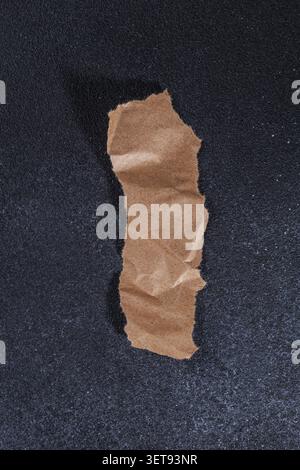 Pezzo di carta Kraft strappato al minimo su sfondo nero Foto Stock