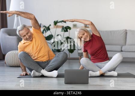 Anziani coppia caucasica che si allunga su tappetini yoga a casa, concetto di stile di vita sano Foto Stock