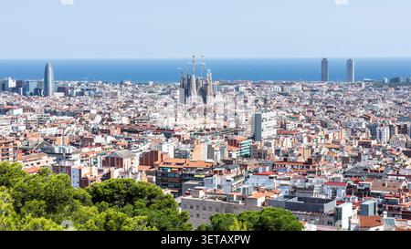 Vista panoramica ad alto angolo del paesaggio urbano di Barcellona con la Sagrada Familia e Torre Glòries contro il Mar Mediterraneo durante una giornata di sole. Foto Stock