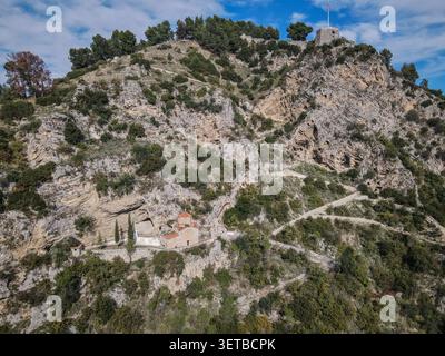 Il Monastero di Ardenica, con il suo caratteristico tetto di tegole rosse, è costruito sul fianco di una ripida montagna rocciosa ricoperta di macchia verde e alberi. A. Foto Stock