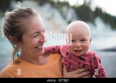 Mamma felice che tiene fuori il suo figlio sorridente Foto Stock