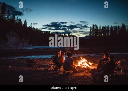 Un gruppo di amici intorno a un fuoco al crepuscolo Foto Stock
