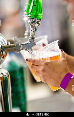 Primo piano di un barista che versa birra alla spina da un rubinetto in una plastica Foto Stock